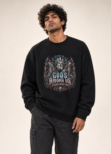 Indian male model front hero wearing PAXBURY Gods Among Us black UH35 oversized unisex crewneck sweatshirt; illustrated crowned stone god and vintage gothic typography centred on chest