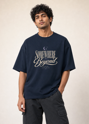 Indian male model standing in PAXBURY Somewhere Beyond navy UC22 oversized T-shirt with original-style vintage cream SOMEWHERE Beyond front lettering