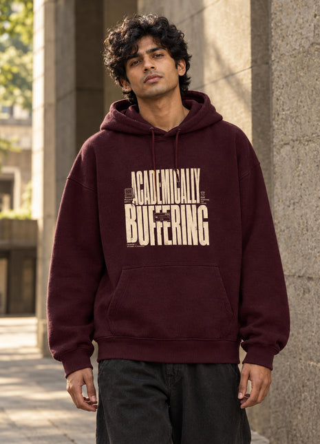 Indian male wearing Buffering Offbeat deep maroon oversized hoodie with cream typographic loading and BUFFERING print