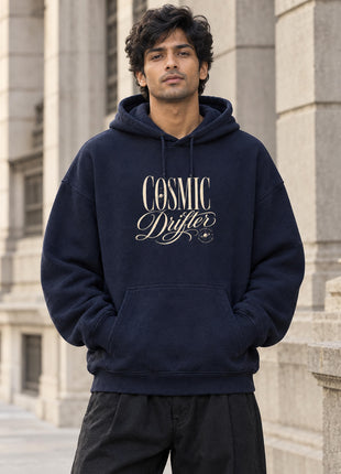 Indian male model wearing Cosmic Drifter navy oversized hoodie, cream COSMIC Drifter serif and script front lettering