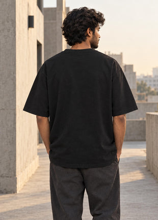 Indian male model showing plain, unprinted black back of Gravity Is Optional oversized T-shirt