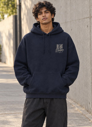 Indian male model wearing navy Heart of the Dragon hoodie, small cream left-chest typographic print on front