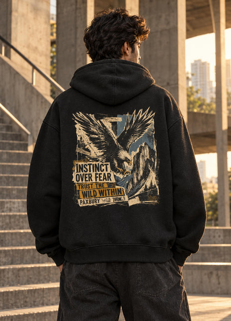 Indian male model wearing Instinct Over Fear black oversized hoodie, large bird-in-flight and landscape back print