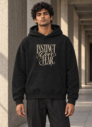 Indian male model wearing Instinct Over Fear black UH32 hoodie with cream typographic print on front