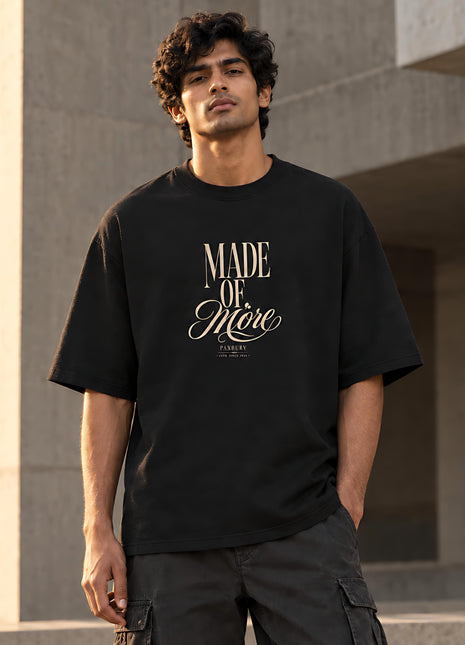 Indian male model in Made of More black oversized T-shirt with cream MADE OF More typography and small PAXBURY detail underneath