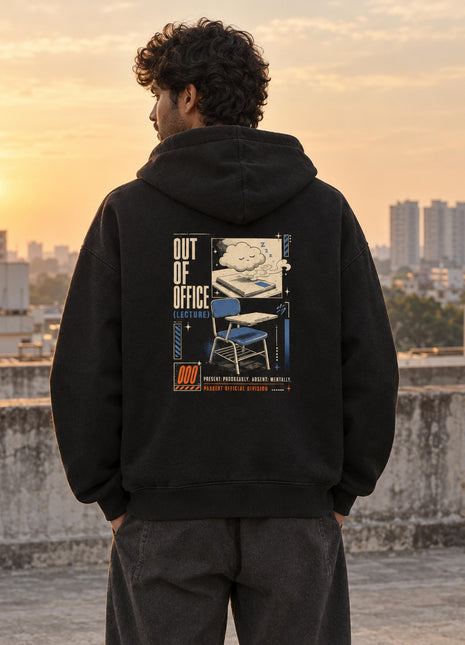 Indian male model wearing black Out of Office oversized hoodie with travel scene, folding chair and OUT OF OFFICE back artwork
