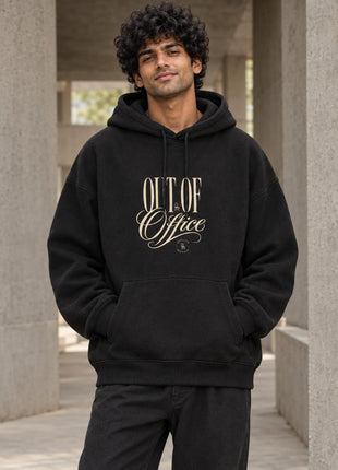 Indian male wearing Out of Office black oversized hoodie with cream OUT OF Office typographic front print