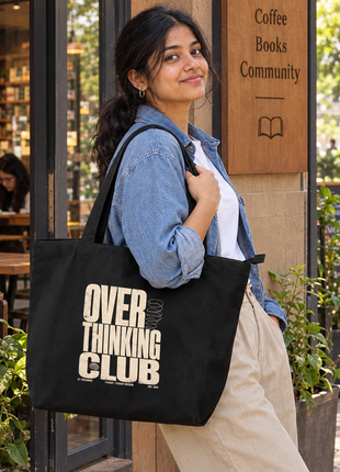 Overthinking Club large black tote: bold reverse print, Indian woman standing beside bookstore café