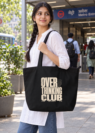 Overthinking Club black large tote: bold back artwork, young Indian woman standing outside city metro