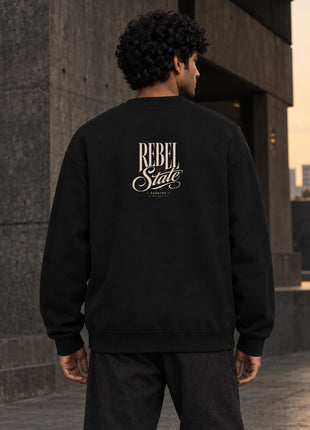 Indian male showing Rebel State black sweatshirt back with small cream REBEL State script signature