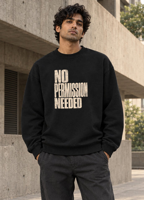 Indian male wearing Rebel State No Permission Needed black oversized crewneck sweatshirt, bold distressed cream front lettering