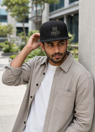 Indian man leaning in office courtyard in PAXBURY Rise of the Phoenix black cotton snapback cap