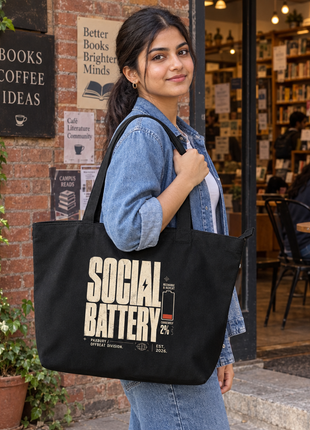 Social Battery large black tote bold reverse typography — Indian young woman standing at a bookshop café