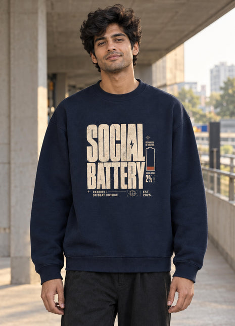Indian male model wearing Social Battery navy oversized crewneck sweatshirt with cream distressed text and orange low battery graphic
