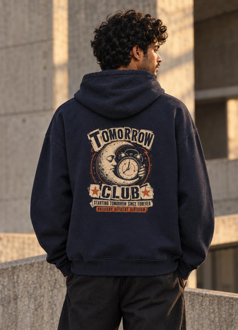 Indian male wearing navy Tomorrow Club oversized hoodie with vintage crescent moon, clock and starry TOMORROW CLUB back artwork